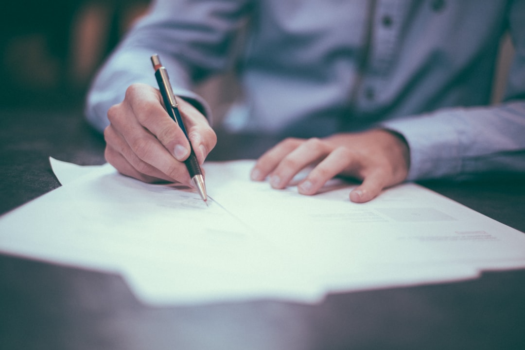 A hand signing a paper form with a pen, a signature on a membership form