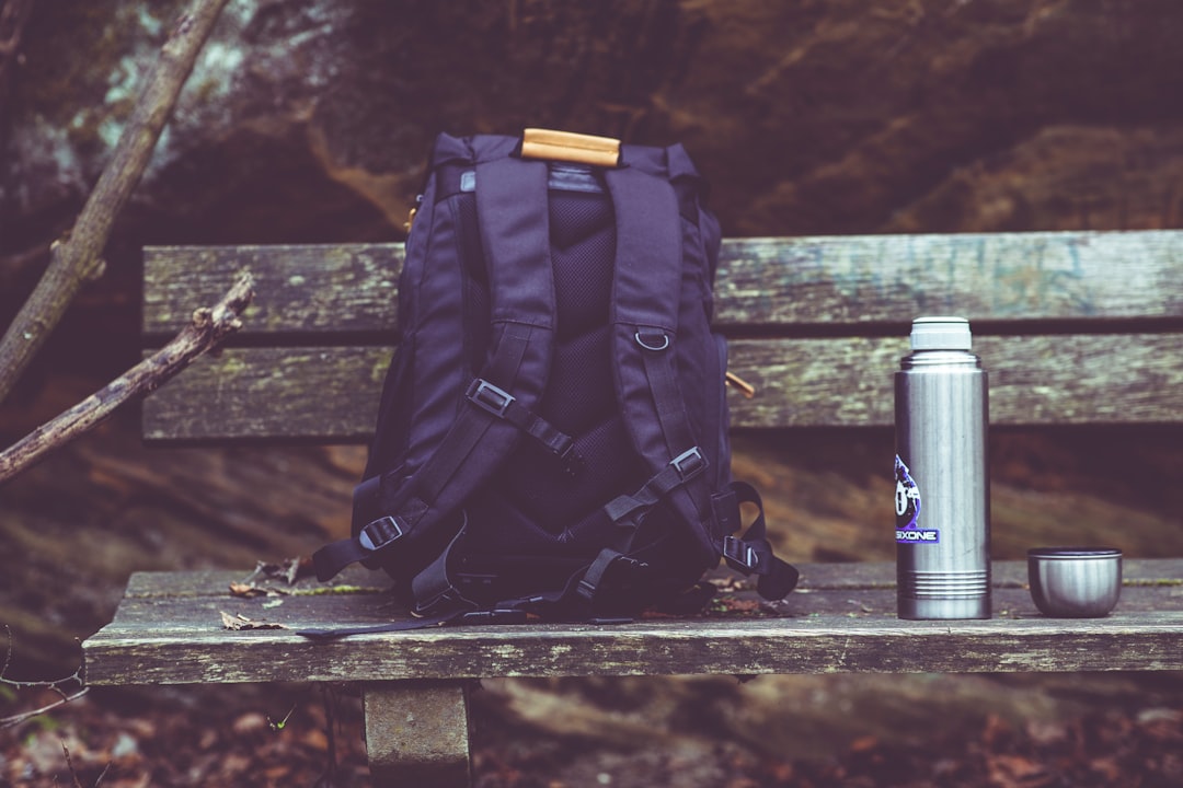 A canvas backpack sitting on a wooden bench, waiting for a campus day