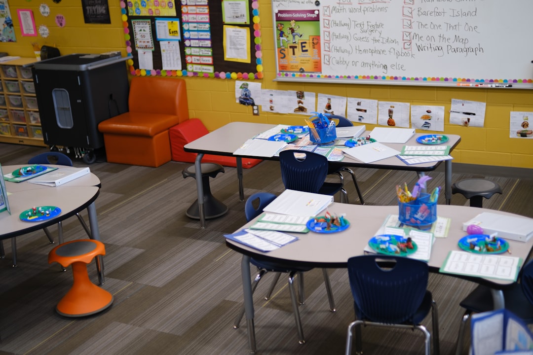 Small tables with folders and school supplies laid out in an empty classroom, one room with every grade at its own table