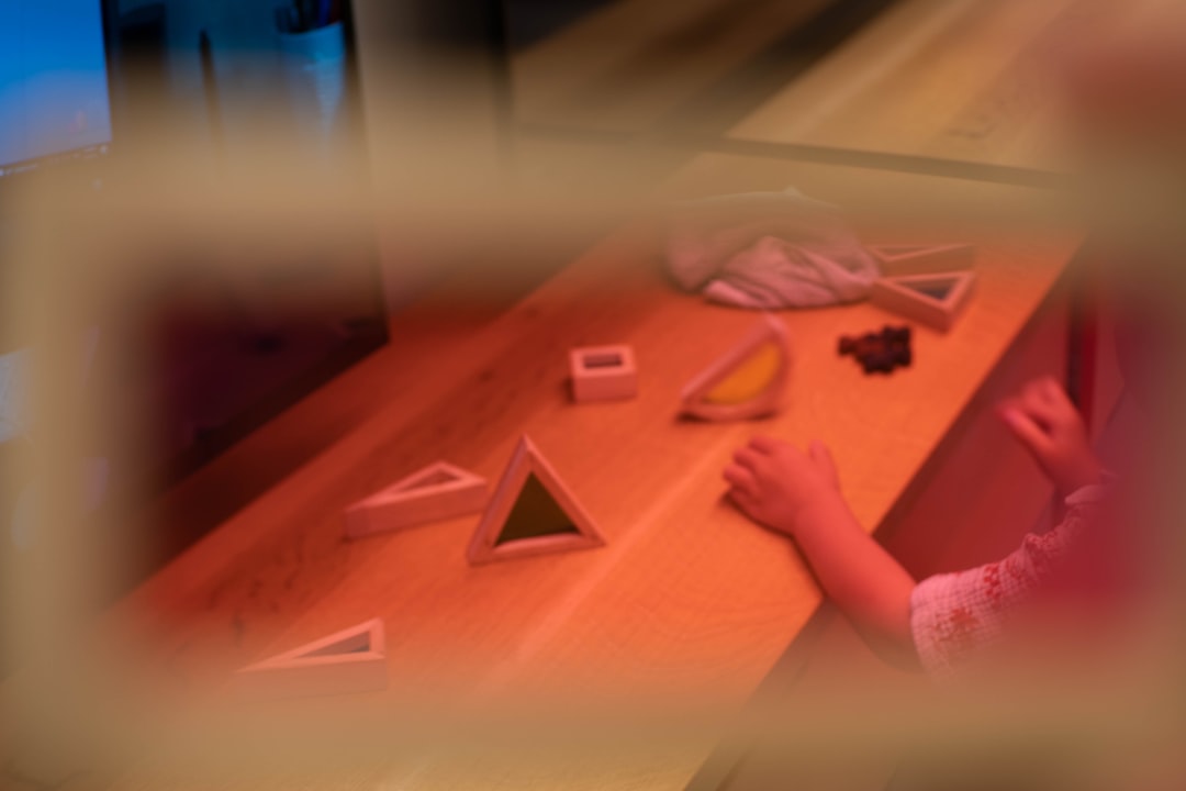 A child's hands arranging colorful wooden blocks on a table, work chosen from the shelf and in progress