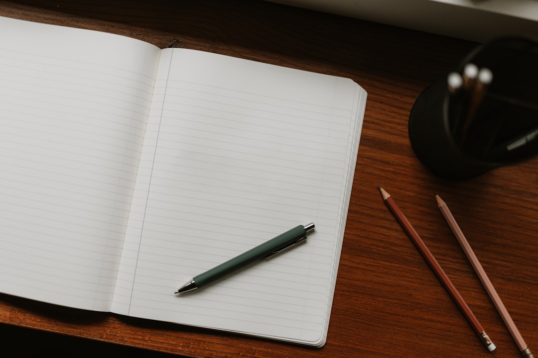 An open notebook with a pen and pencils on a wooden desk, the registrar's desk between report card periods