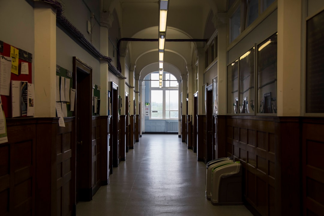 Rows of empty wooden chairs in a bright campus hallway between class periods